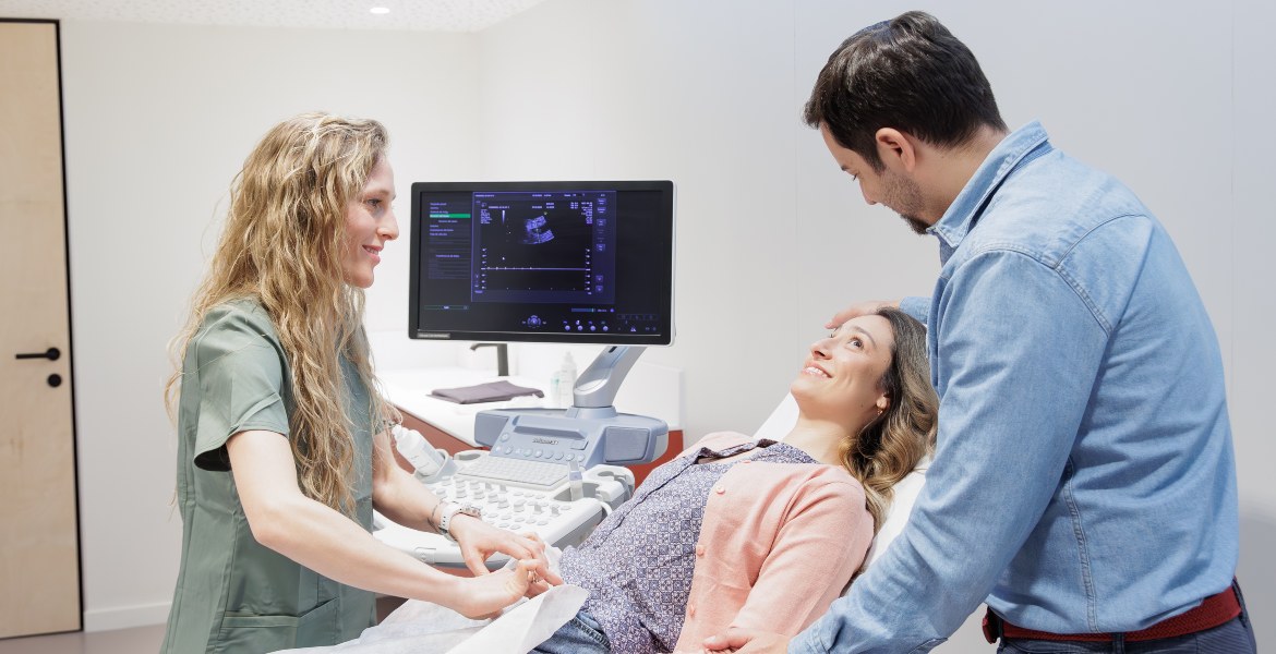 Coppia assiste una donna durante l’ecografia eseguita dal personale medico presso la clinica Barcelona IVF.