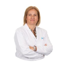 La dottoressa Ana Teresa Almeida di Eugin Coimbra indossa un camice bianco da medico, con le braccia incrociate, su sfondo bianco.